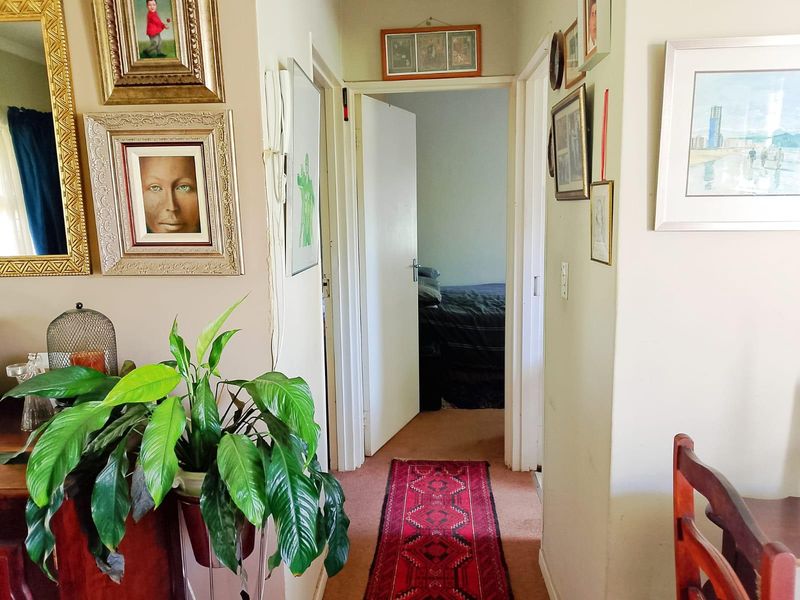 A functional residential hallway connecting living areas to bedrooms, featuring carpeted flooring and standard internal door access.