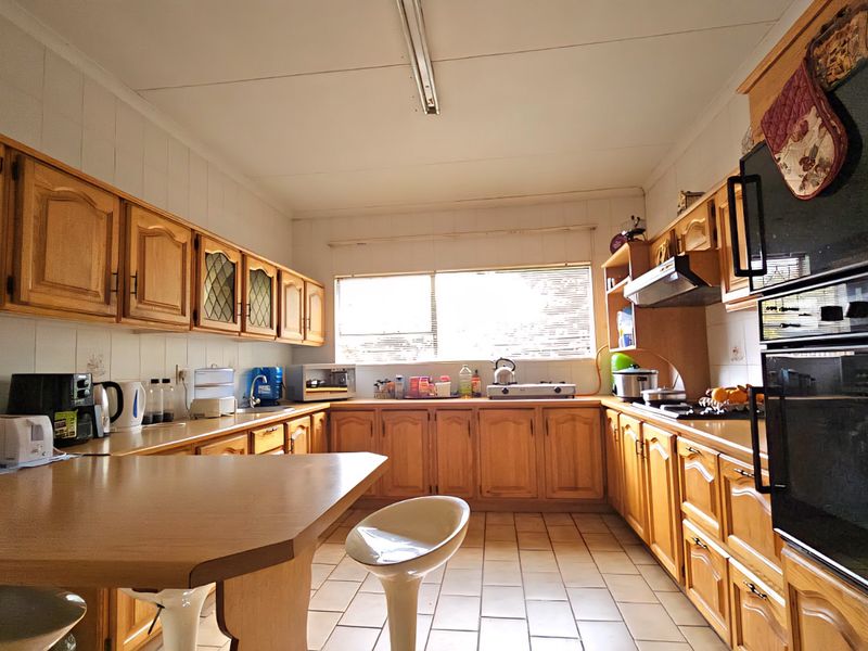 A functional kitchen featuring traditional wooden cabinetry, tiled flooring, a built-in double oven, and a convenient breakfast nook area.