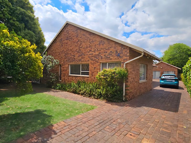 A well-maintained face brick house featuring a paved driveway, established garden, and a detached garage, showcasing classic exterior architecture.