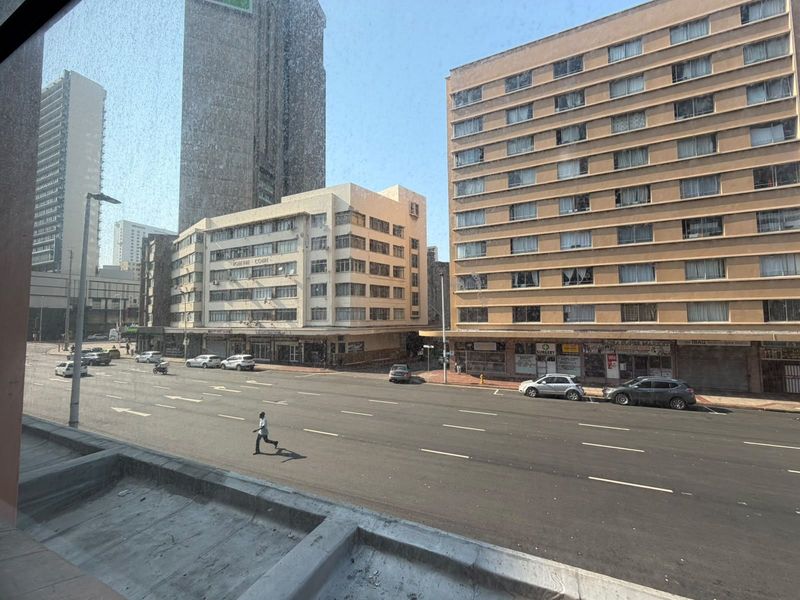 An elevated street view looking out over a busy urban intersection with surrounding multi-story apartment buildings and commercial storefronts.