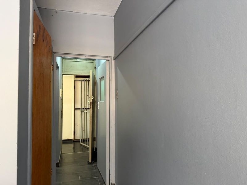 A functional hallway featuring tiled flooring and a security gate, providing access to the apartment entrance.