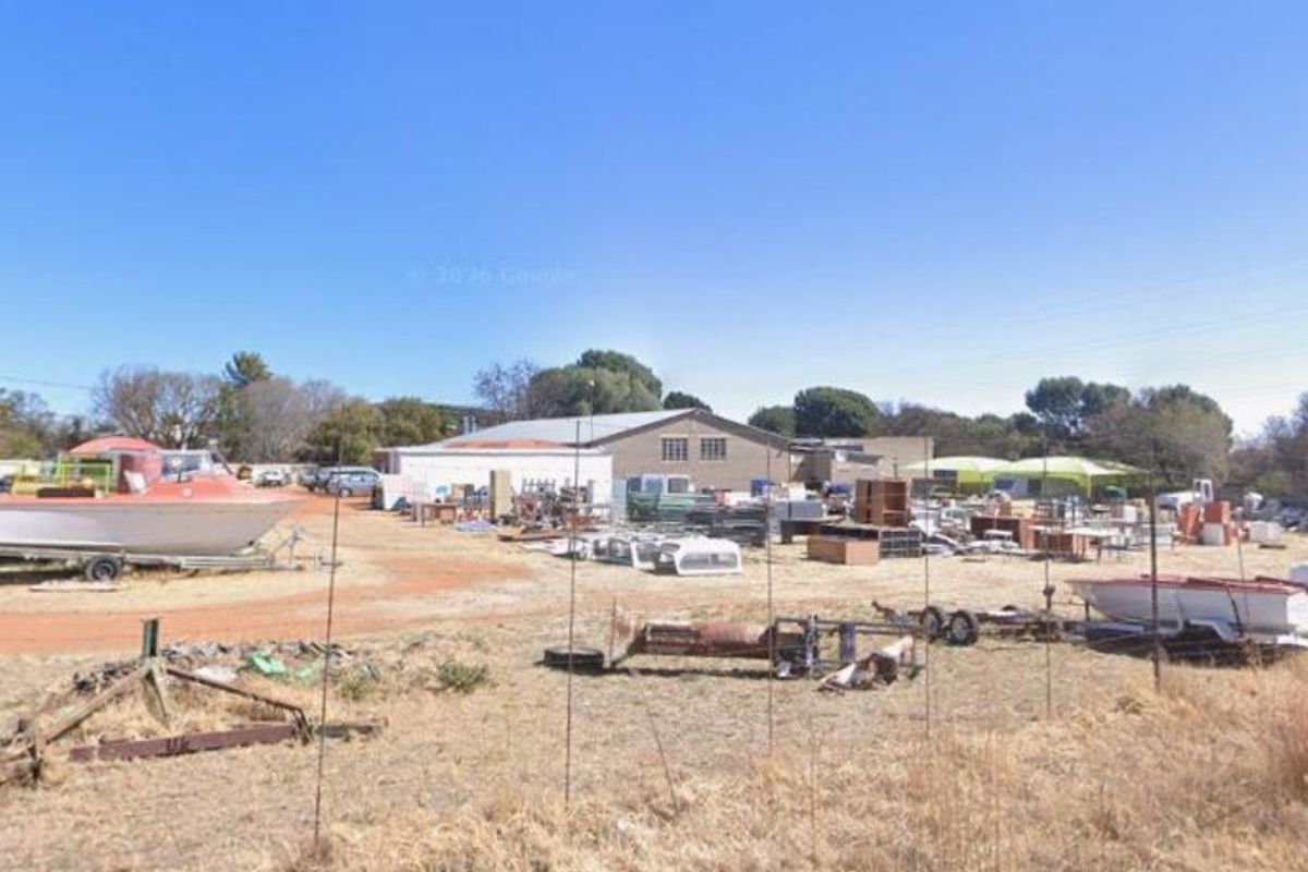 A wide view of a commercial property exterior featuring a large open yard area and a central industrial building structure.