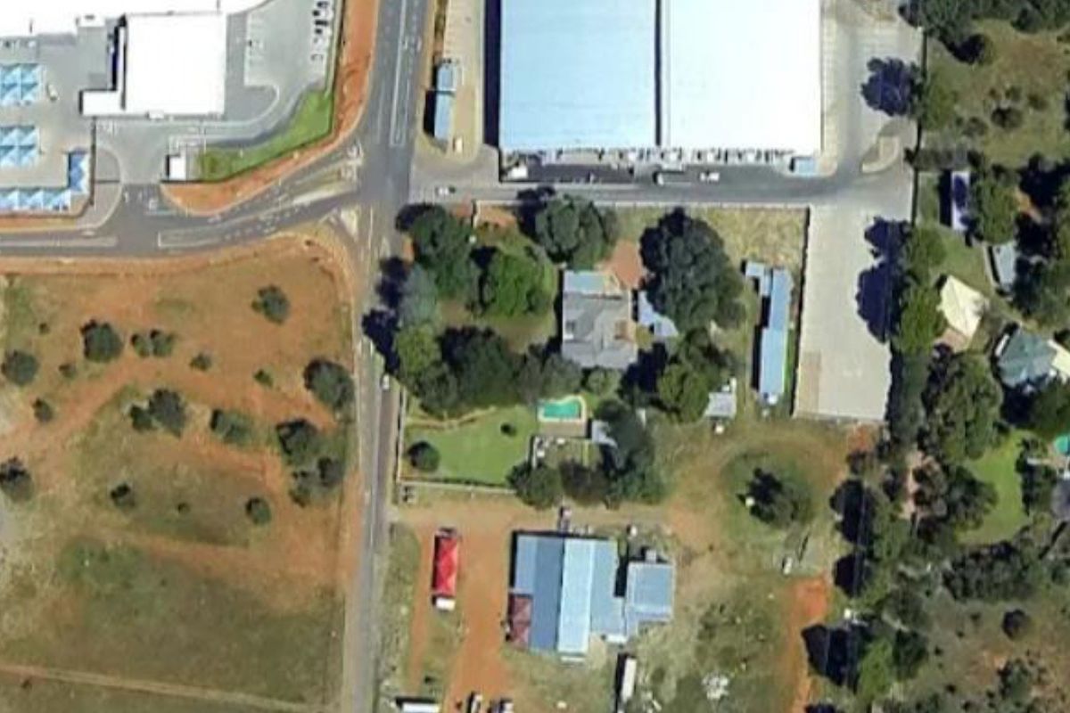 Aerial view of a commercial property complex featuring multiple warehouse structures, a swimming pool, and surrounding landscaped grounds.