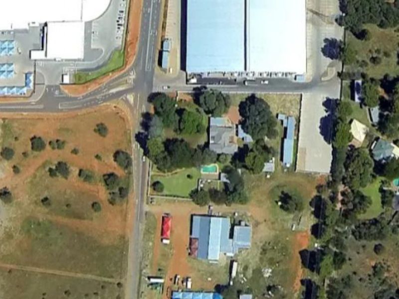 Aerial view of a commercial property complex featuring multiple warehouse structures, a swimming pool, and surrounding landscaped grounds.