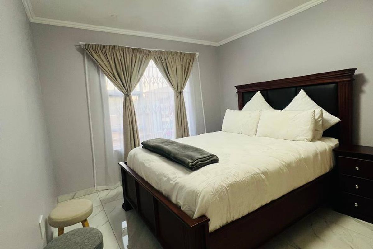 A well-maintained bedroom featuring polished marble-look floor tiles, neutral wall finishes, and a secure window with fitted security gate.