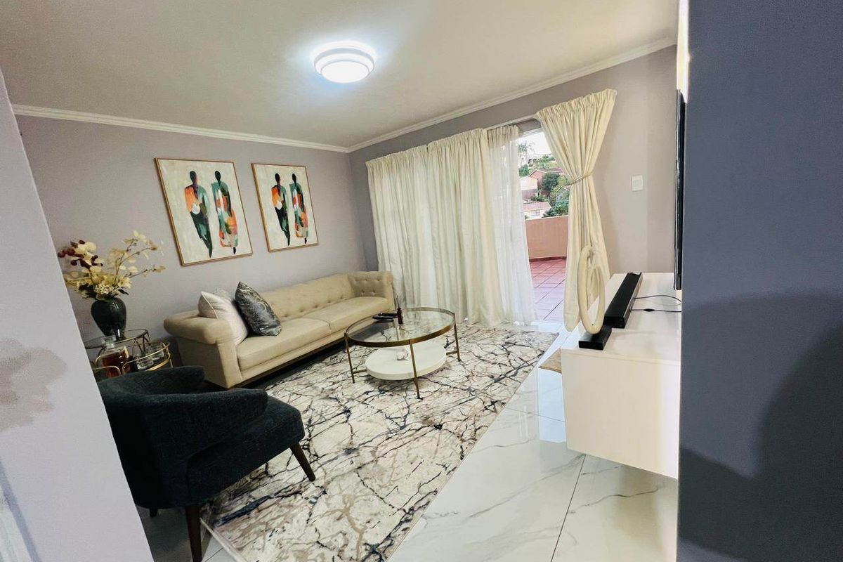 A well-maintained living room featuring polished marble-look floor tiles and a sliding glass door providing access to an outdoor balcony area.