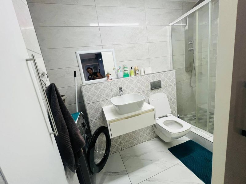 Modern bathroom featuring a wall-mounted vanity with vessel sink, wall-hung toilet, and a glass-enclosed shower with contemporary tiled finishes.