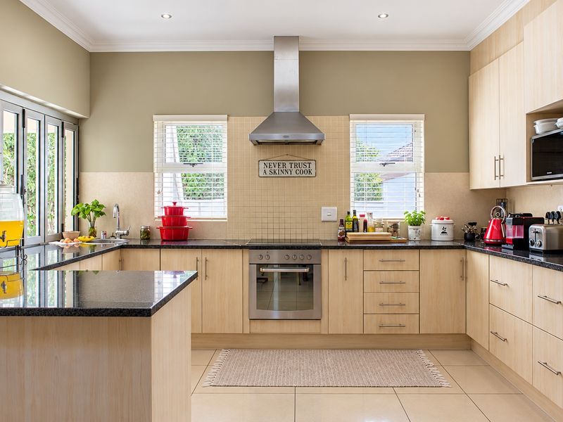 A well-maintained kitchen featuring light wood cabinetry, granite countertops, stainless steel appliances, and ample natural light from dual windows.