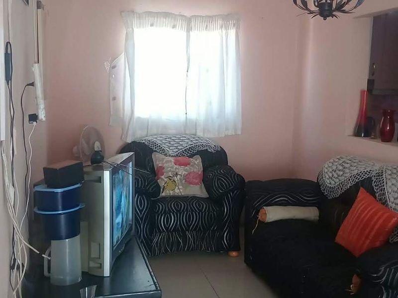 A compact living room featuring tiled flooring and a convenient pass-through window connecting to the kitchen area.