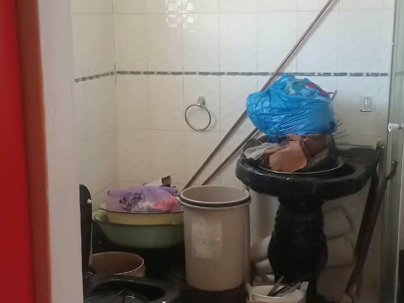 A small bathroom featuring a pedestal basin, toilet, and shower enclosure with white wall and floor tiling.