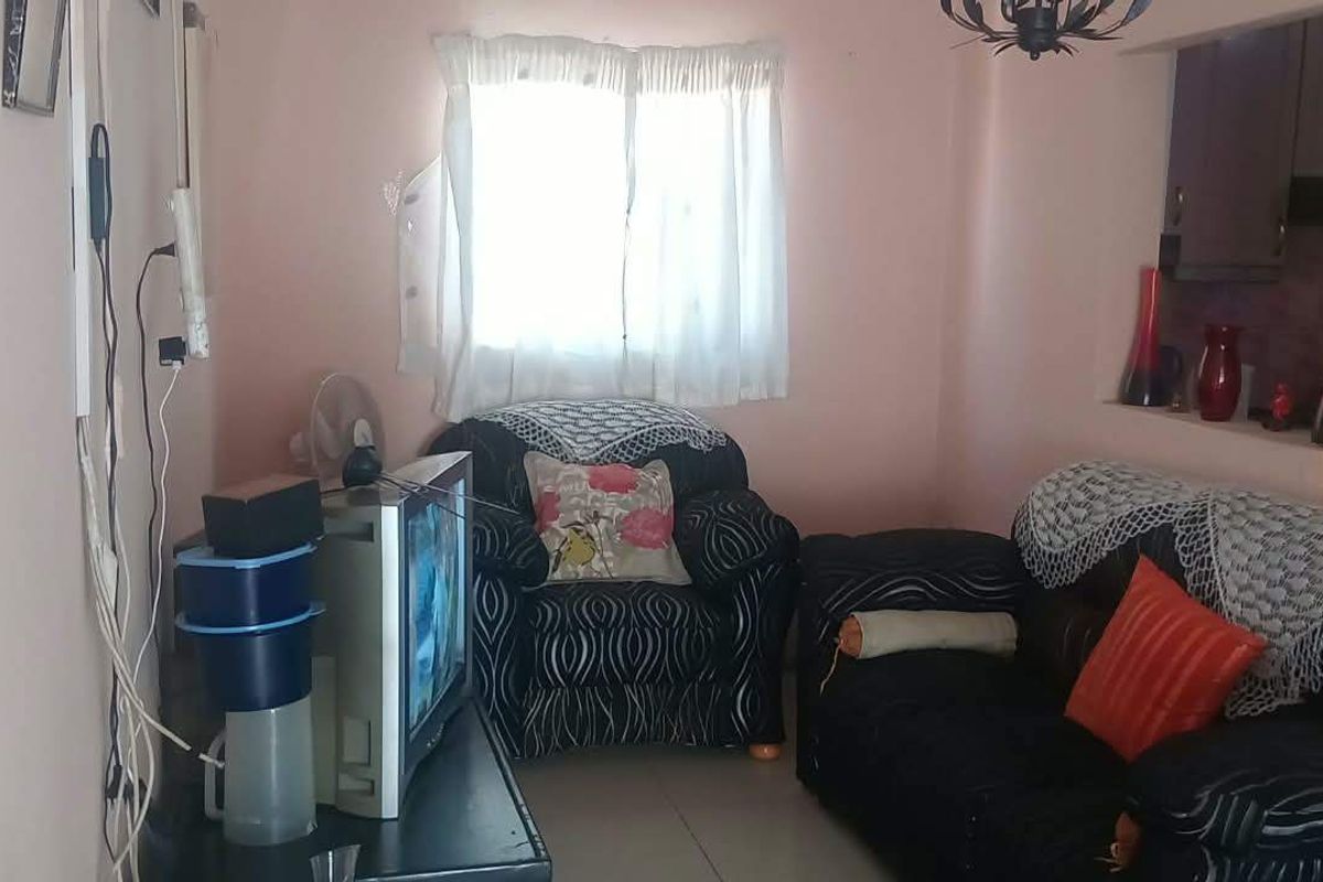 A compact living room featuring tiled flooring and a convenient pass-through window connecting to the kitchen area.