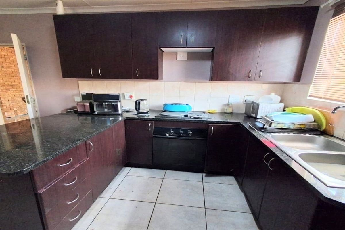 A functional kitchen featuring dark wood cabinetry, granite countertops, a built-in oven, and a double basin sink with tiled backsplash.