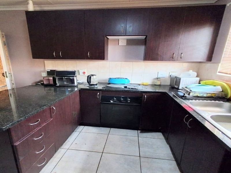 A functional kitchen featuring dark wood cabinetry, granite countertops, a built-in oven, and a double basin sink with tiled backsplash.