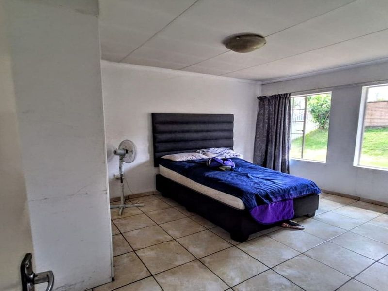 A bedroom featuring tiled flooring and large windows that provide natural light, offering a blank canvas for potential cosmetic updates and modernization.