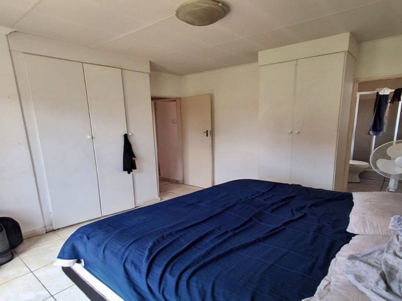 A bedroom featuring built-in cupboards, tiled flooring, and direct access to an en-suite bathroom.