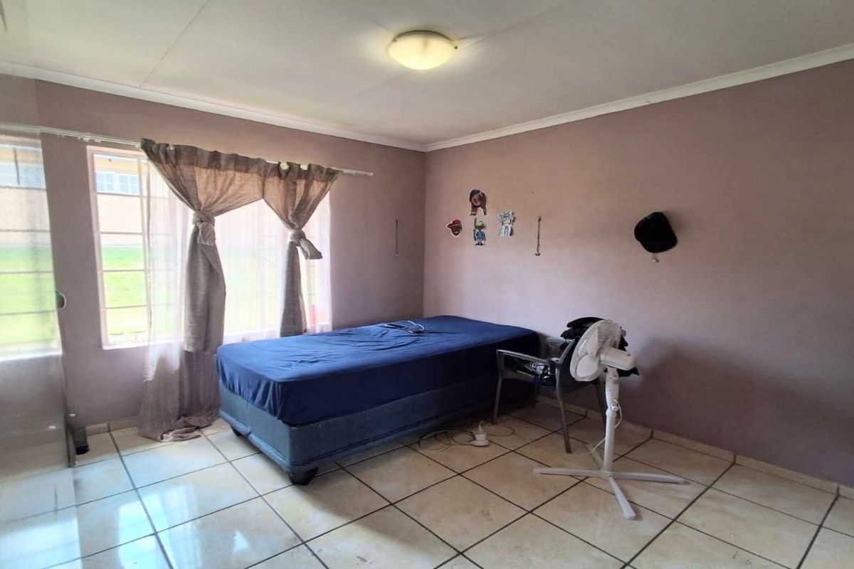 A bedroom featuring tiled flooring and a window, requiring cosmetic updates to the wall finishes to improve the overall aesthetic.