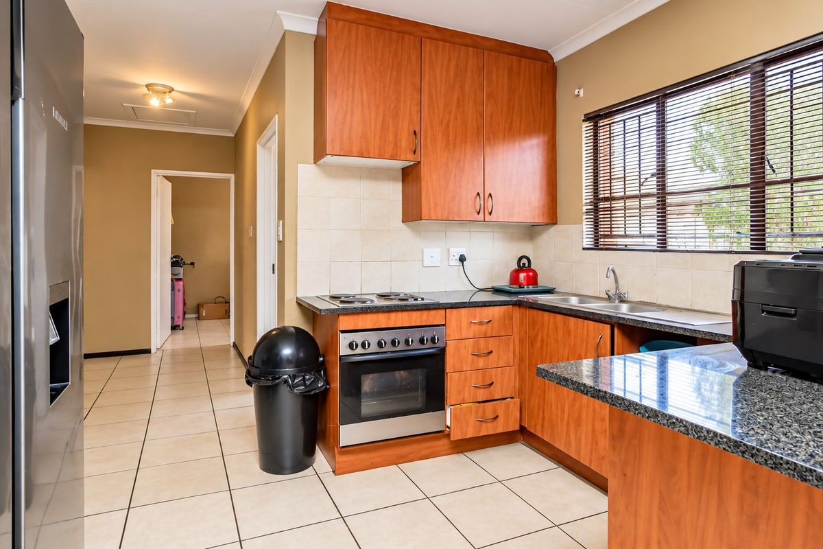 A functional kitchen featuring wood-finish cabinetry, granite countertops, a built-in oven with hob, and tiled flooring, offering a practical layout for daily use.