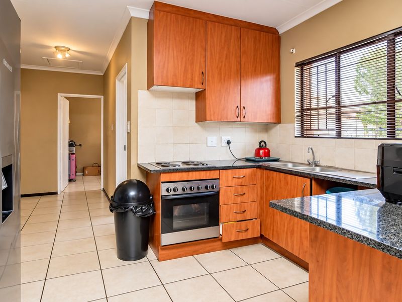 A functional kitchen featuring wood-finish cabinetry, granite countertops, a built-in oven with hob, and tiled flooring, offering a practical layout for daily use.