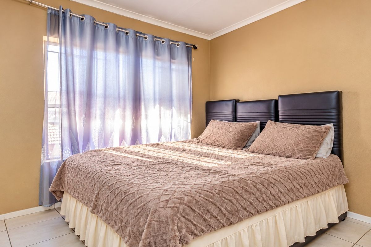 A well-lit bedroom featuring tiled flooring and neutral wall finishes, providing a comfortable and functional sleeping space.
