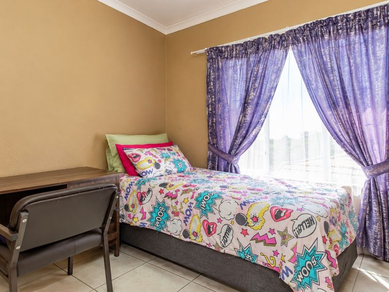 A functional bedroom featuring tiled flooring and a window with installed curtain rods, providing a neutral base for personalization.