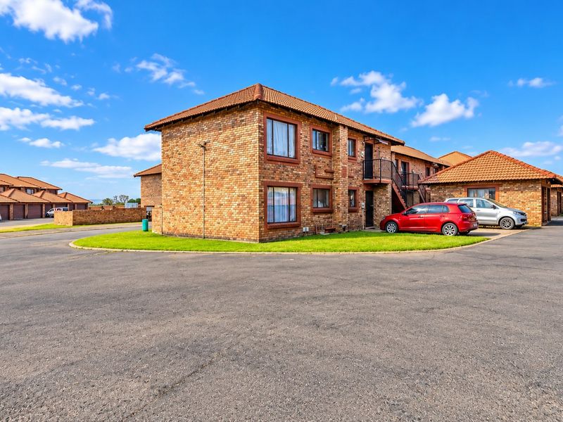 Exterior view of a multi-story face brick apartment complex featuring tiled roofing and paved driveway access.