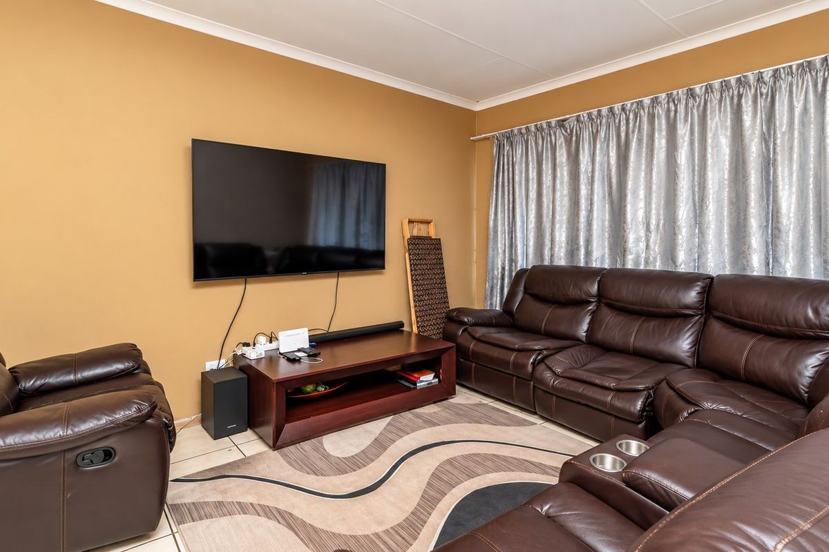 A comfortable living room featuring tiled flooring and coved ceiling details, providing a functional space for relaxation and entertainment.