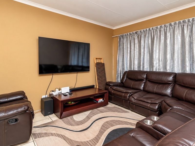 A comfortable living room featuring tiled flooring and coved ceiling details, providing a functional space for relaxation and entertainment.