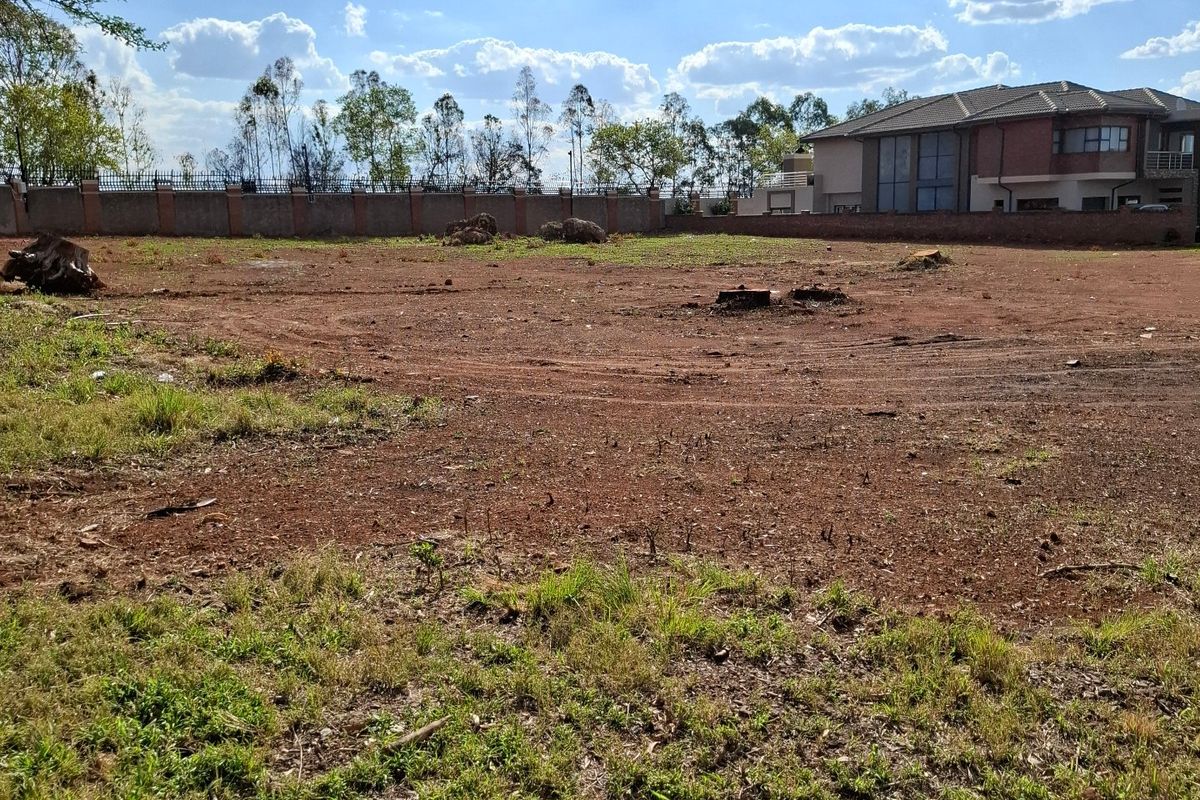 A vacant residential plot featuring cleared ground and a perimeter boundary wall, offering a blank canvas for future development.