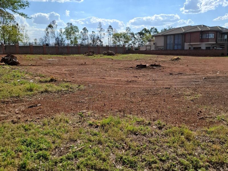 A vacant residential plot featuring cleared ground and a perimeter boundary wall, offering a blank canvas for future development.