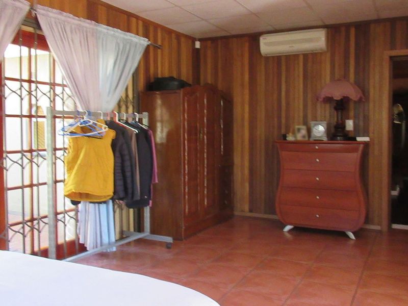 Bedroom featuring wood-paneled walls, tiled flooring, and a split-system air conditioner, with access to an outdoor area through security-gated french doors.