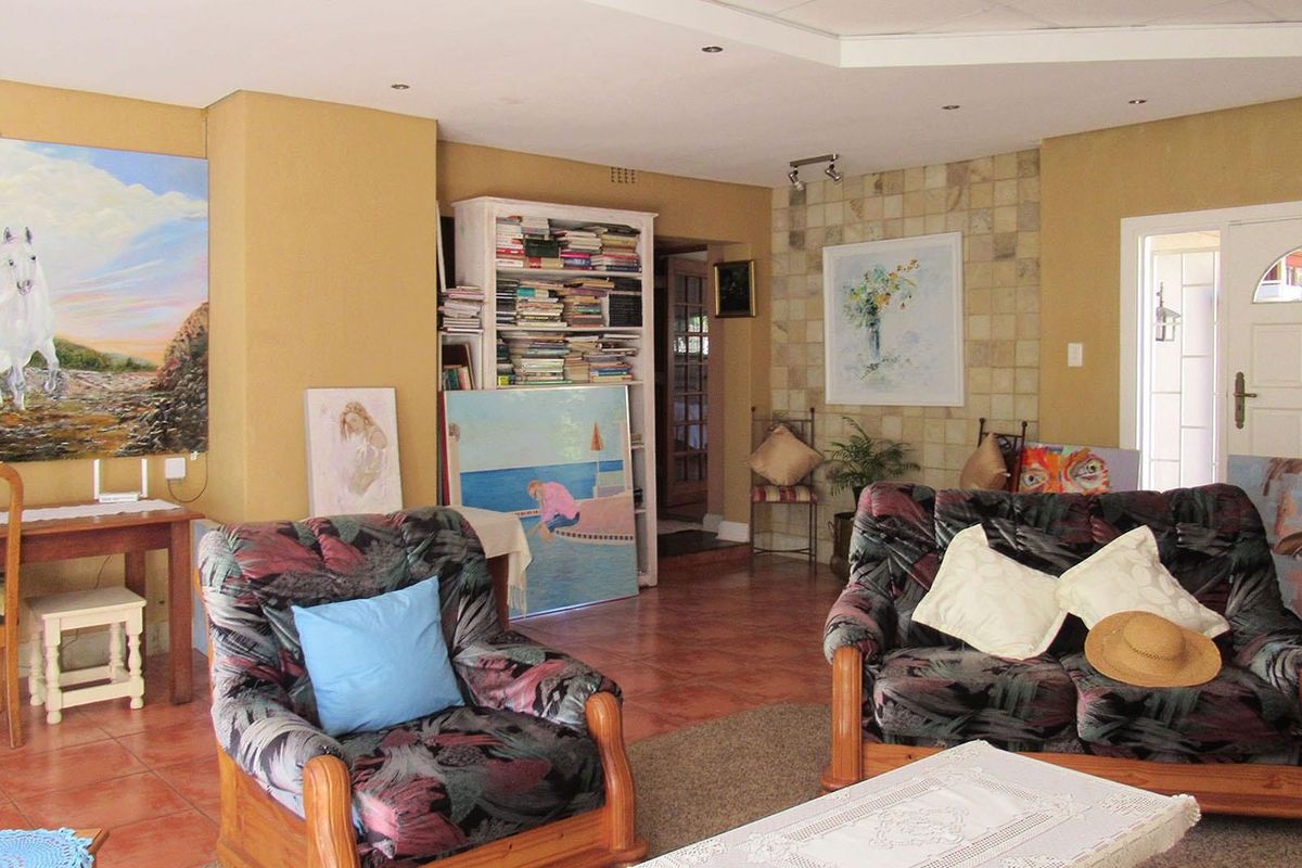 Spacious living area featuring tiled flooring, a stone accent wall, recessed lighting, and a built-in shelving unit, offering a versatile layout for relaxation.