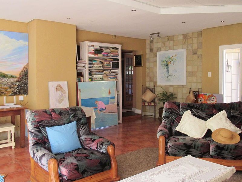 Spacious living area featuring tiled flooring, a stone accent wall, recessed lighting, and a built-in shelving unit, offering a versatile layout for relaxation.