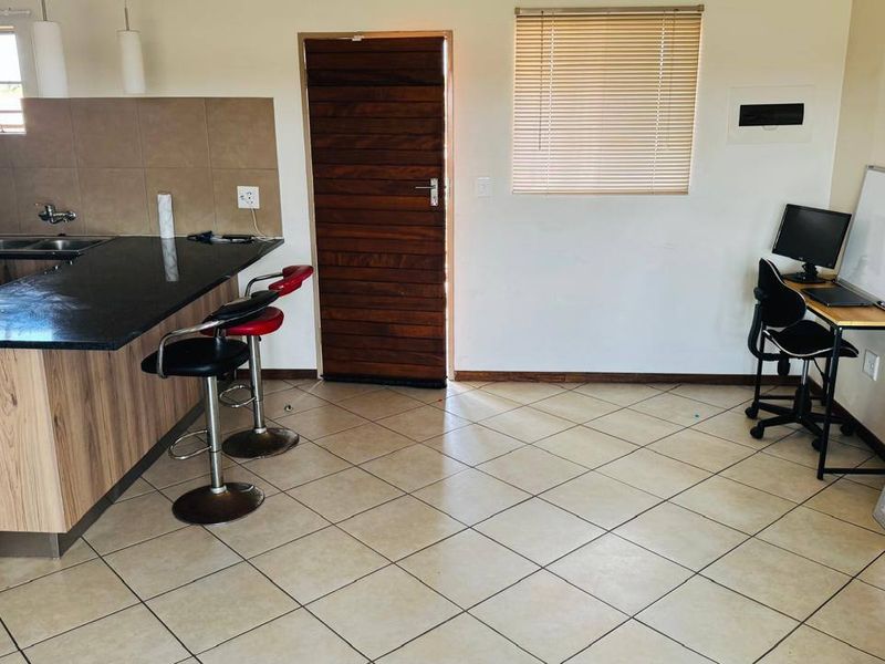 Open plan kitchen and living area featuring granite countertops, tiled flooring, and neutral finishes, providing a functional and versatile space.