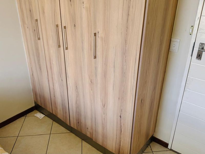 A bedroom featuring a modern wood-grain built-in wardrobe and neutral tiled flooring.