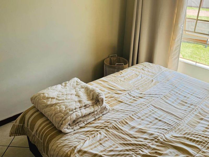 A bedroom featuring tiled flooring and a large window allowing natural light, providing a comfortable and functional living space.