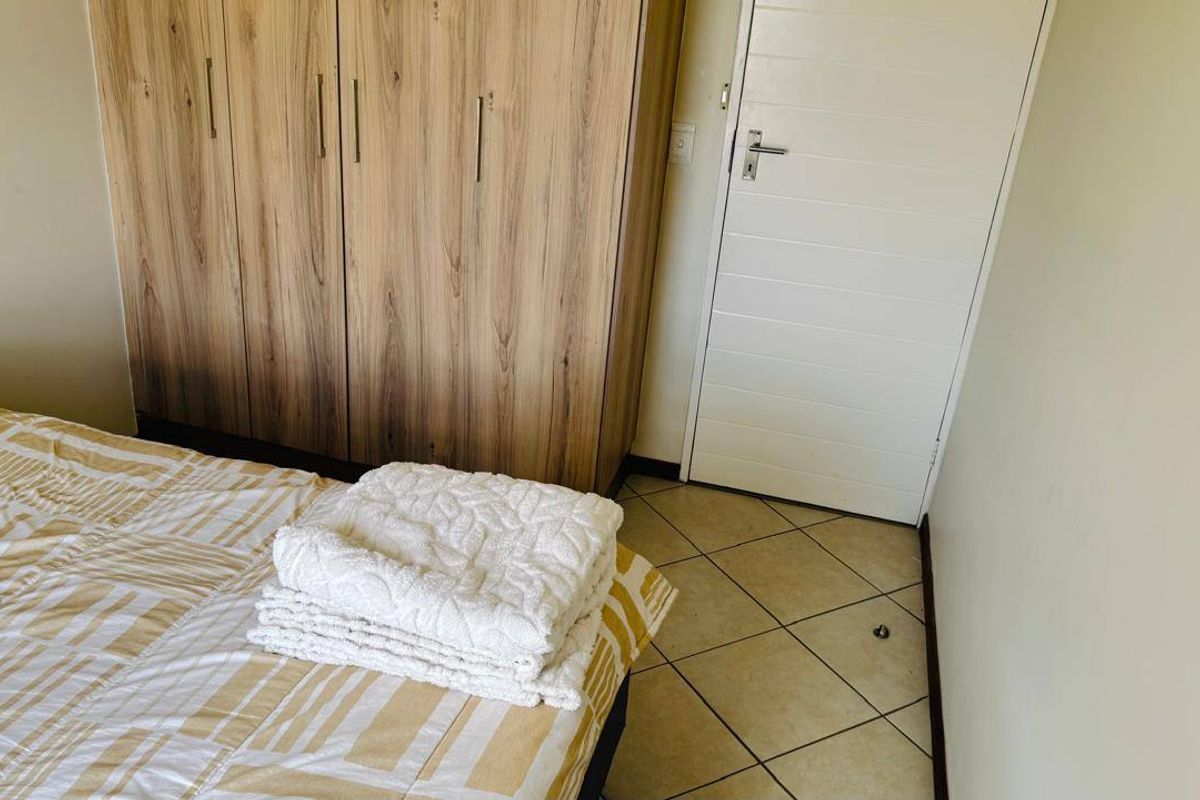 A bedroom featuring built-in wooden cupboards, tiled flooring, and a white internal door.