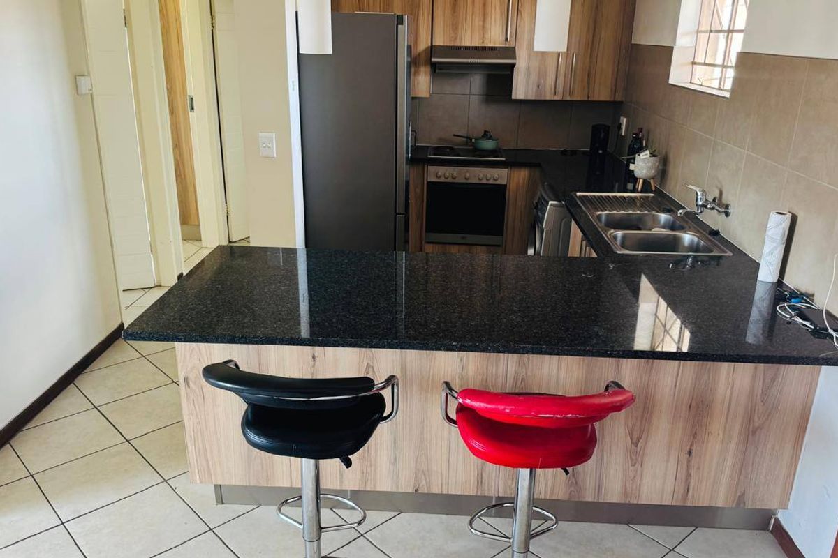 A functional kitchen featuring wood-look cabinetry, dark granite countertops, a double basin sink, and built-in cooking appliances with a tiled backsplash.
