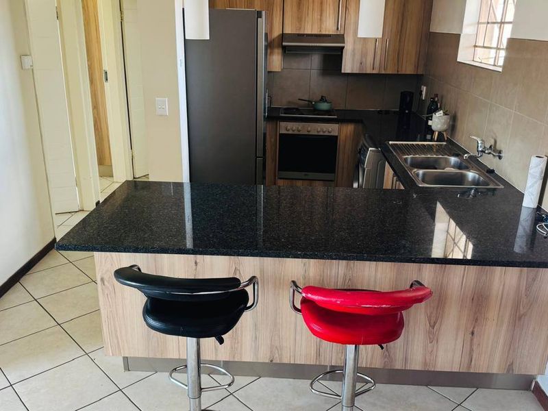 A functional kitchen featuring wood-look cabinetry, dark granite countertops, a double basin sink, and built-in cooking appliances with a tiled backsplash.