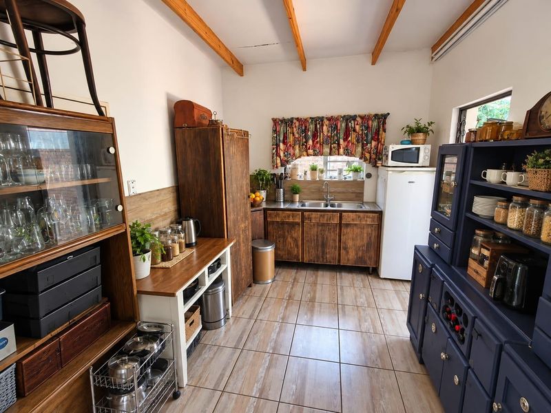 A rustic-style kitchen featuring wooden cabinetry, tiled flooring, and exposed ceiling beams, providing a warm and functional cooking space.