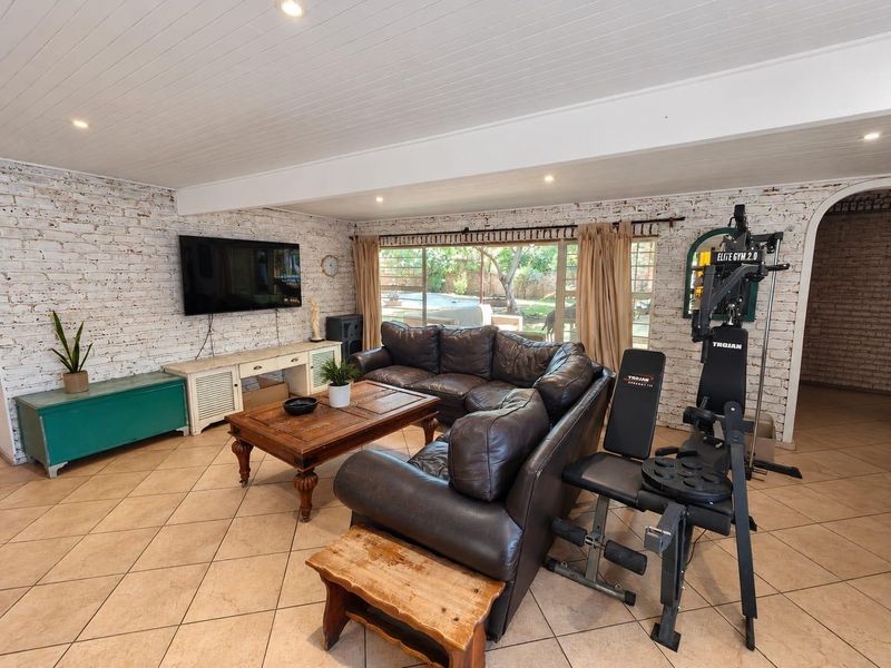 Spacious living room featuring exposed brick walls, tiled flooring, and large sliding doors providing natural light and access to the outdoor area.