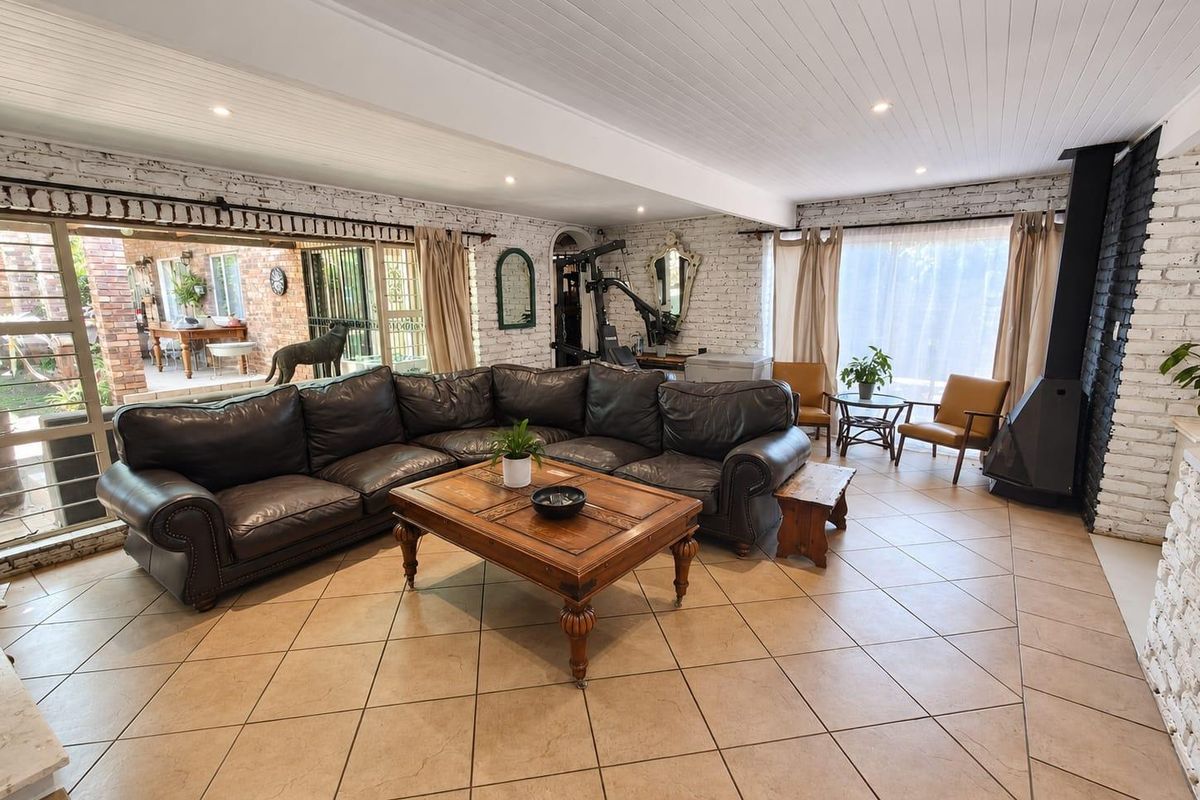 Spacious living room featuring exposed white brick walls, tiled flooring, a modern wood-burning fireplace, and large sliding doors opening to an outdoor patio area.