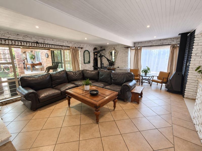Spacious living room featuring exposed white brick walls, tiled flooring, a modern wood-burning fireplace, and large sliding doors opening to an outdoor patio area.