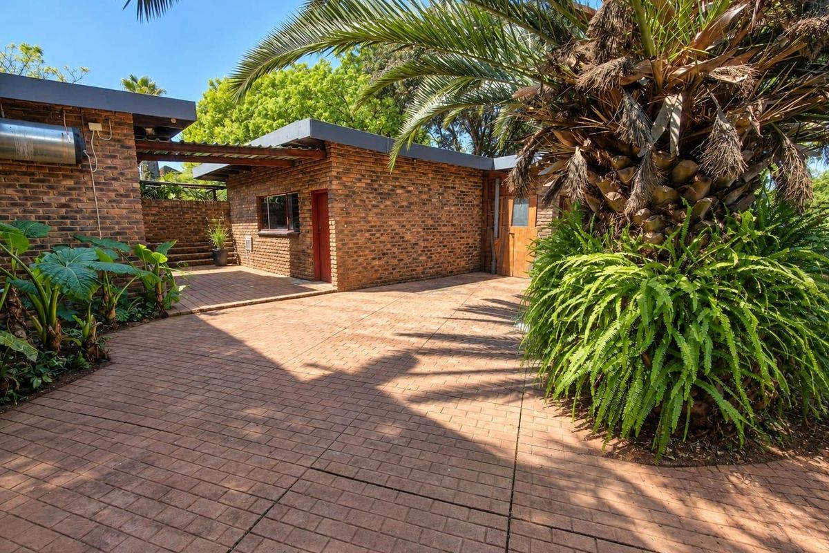 A well-maintained rear courtyard featuring exposed brick walls, paved flooring, and a timber pergola, providing a private outdoor space.