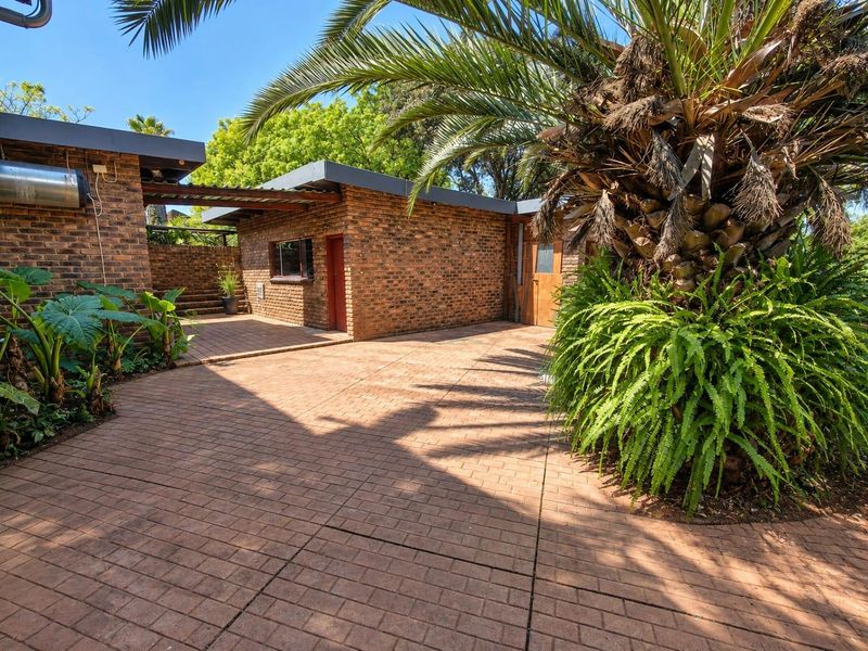 A well-maintained rear courtyard featuring exposed brick walls, paved flooring, and a timber pergola, providing a private outdoor space.