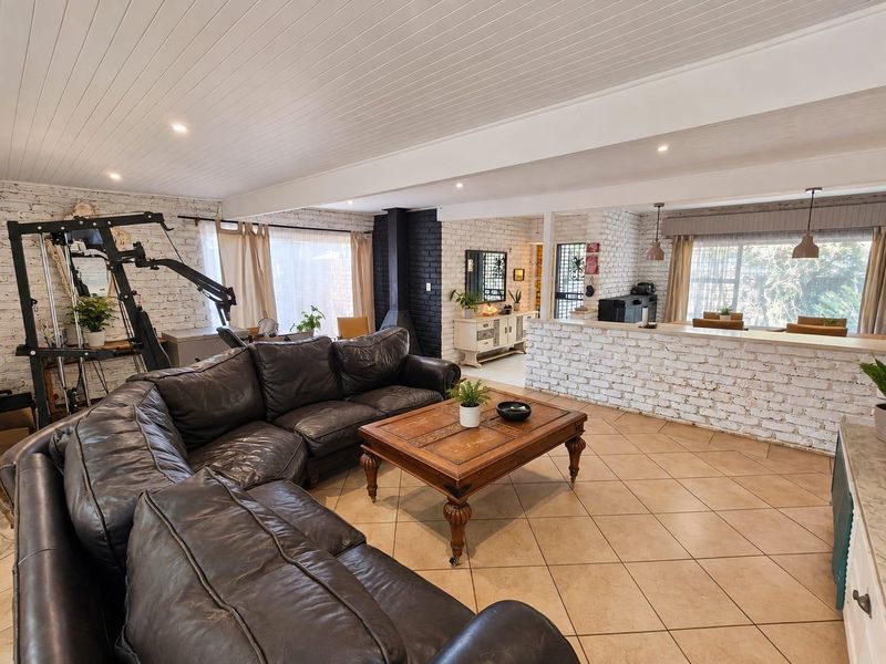 Spacious open-plan living area featuring exposed brick walls, a wood-burning fireplace, tiled flooring, and a breakfast bar connecting to the kitchen.