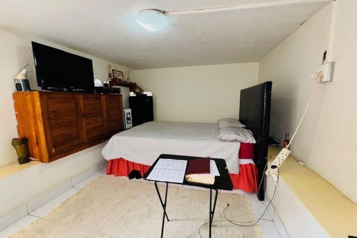 A bedroom featuring a built-in raised platform, tiled flooring, and exposed electrical wiring, requiring cosmetic updates to improve the overall finish and aesthetic appeal.