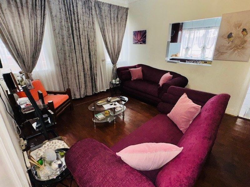 A cozy living room featuring dark hardwood flooring and a convenient serving hatch connecting to the kitchen area.