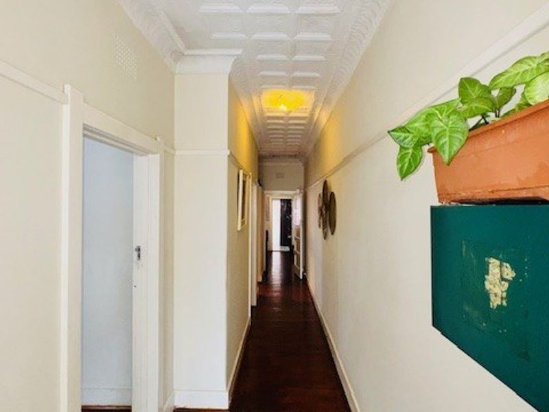 A long hallway featuring traditional pressed metal ceilings, timber flooring, and classic picture rails, providing a character-filled transition between rooms.