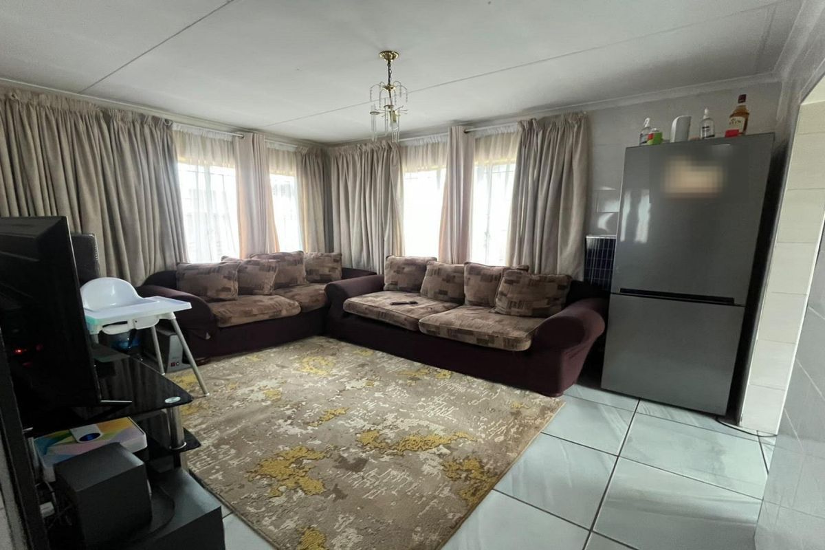 A living room featuring tiled flooring and large windows with curtain rails, providing a functional space for relaxation.