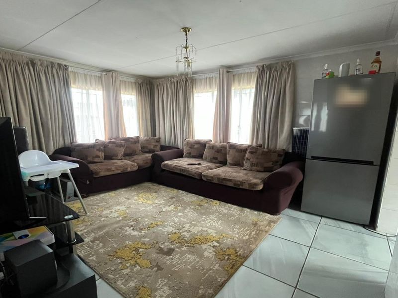 A living room featuring tiled flooring and large windows with curtain rails, providing a functional space for relaxation.